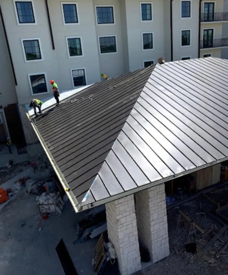 Crew installing standing seam metal roof panels on a commercial project in Birmingham